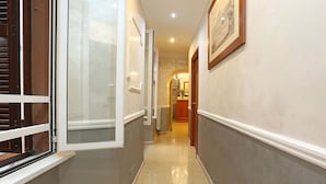 A hallway with a tiled floor, a door with a white frame, and a wall-mounted picture. - AdoraSuite B&B (Rome)