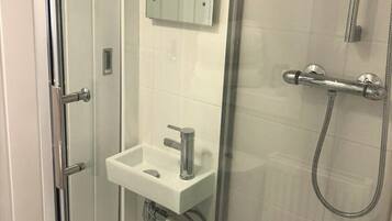 A glass-enclosed shower with a white sink and a mirror above it.