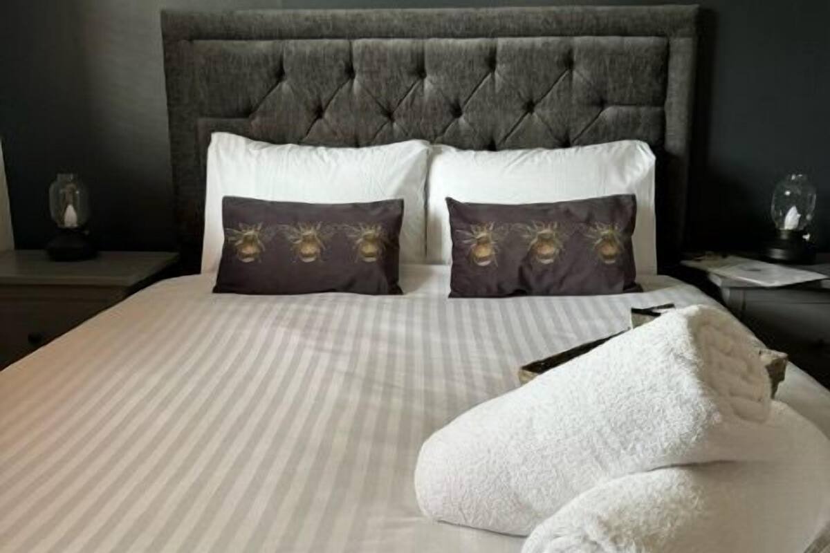 A neatly made bed with striped bedding, two white pillows, and two brown pillows with a floral design.