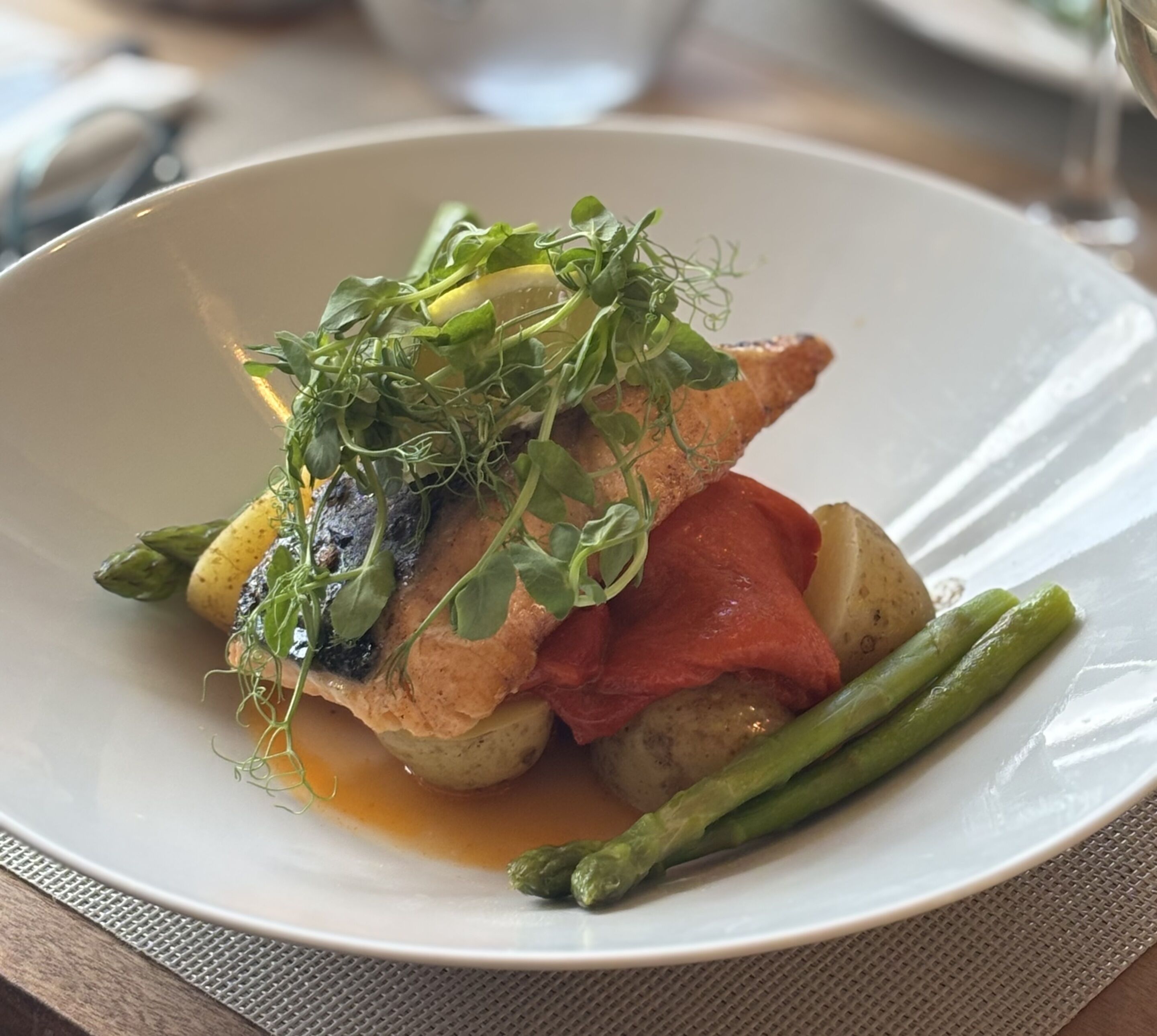 Un plato de comida con pescado, espárragos y patatas.