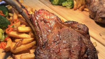 A wooden cutting board with a grilled steak, French fries, and broccoli.