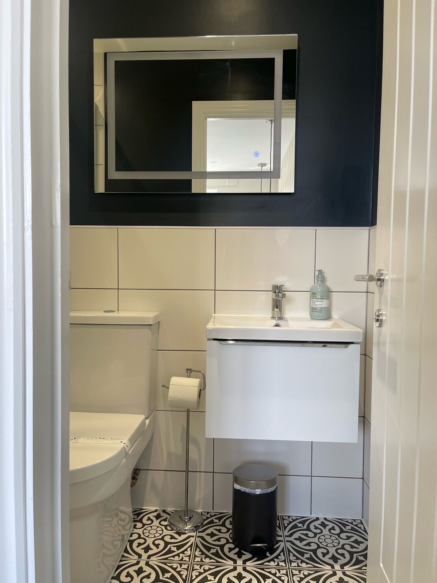 Un baño pequeño y moderno con inodoro, lavamanos y espejo.
