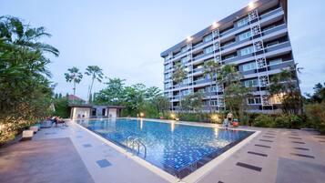 Una piscina al aire libre, sombrillas, sillones reclinables de piscina