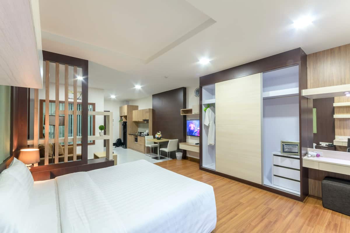 Een hotelkamer met een bed, een bureau, een televisie, een kledingkast en een kleine kitchenette.