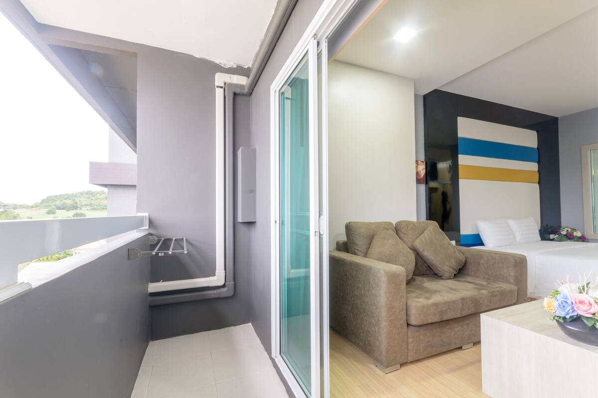 Een moderne kamer met balkon, een bank, een bed en een muur met een blauw-gele streep.