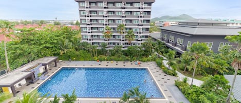 Una piscina al aire libre, sombrillas, sillones reclinables de piscina