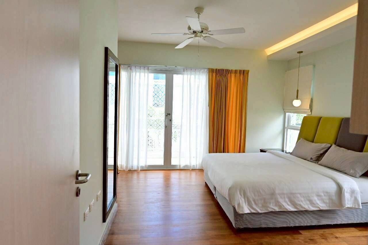 A bedroom with a bed, a ceiling fan, a window with curtains, and a door.