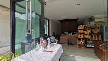 Una cocina moderna con encimera de madera, una zona de comedor con mesa para dos comensales y un rincón de estar con un sofá marrón.