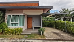 A modern house with a wooden front door, a covered porch, and a well-maintained garden. - Smile Resort Sriracha (Si Racha)