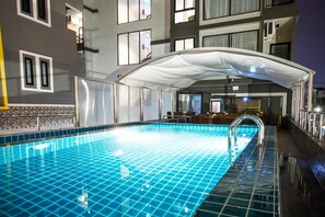 A swimming pool with a white canopy, tiled walls, and a bar area with seating. - Triple B Boutique Residence (Si Racha)