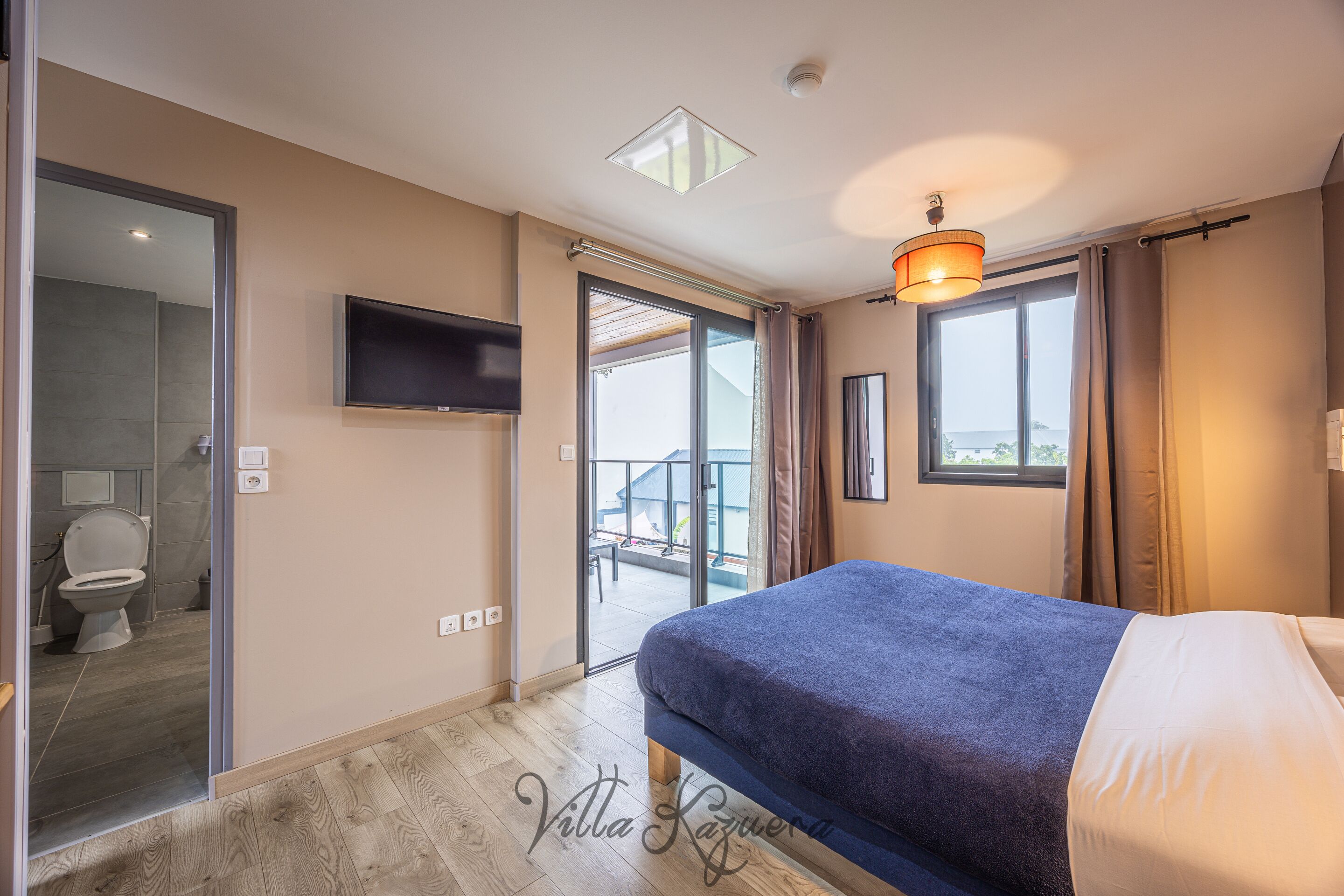 Une chambre à coucher avec un lit, une télévision, un balcon et une vue sur l’extérieur.