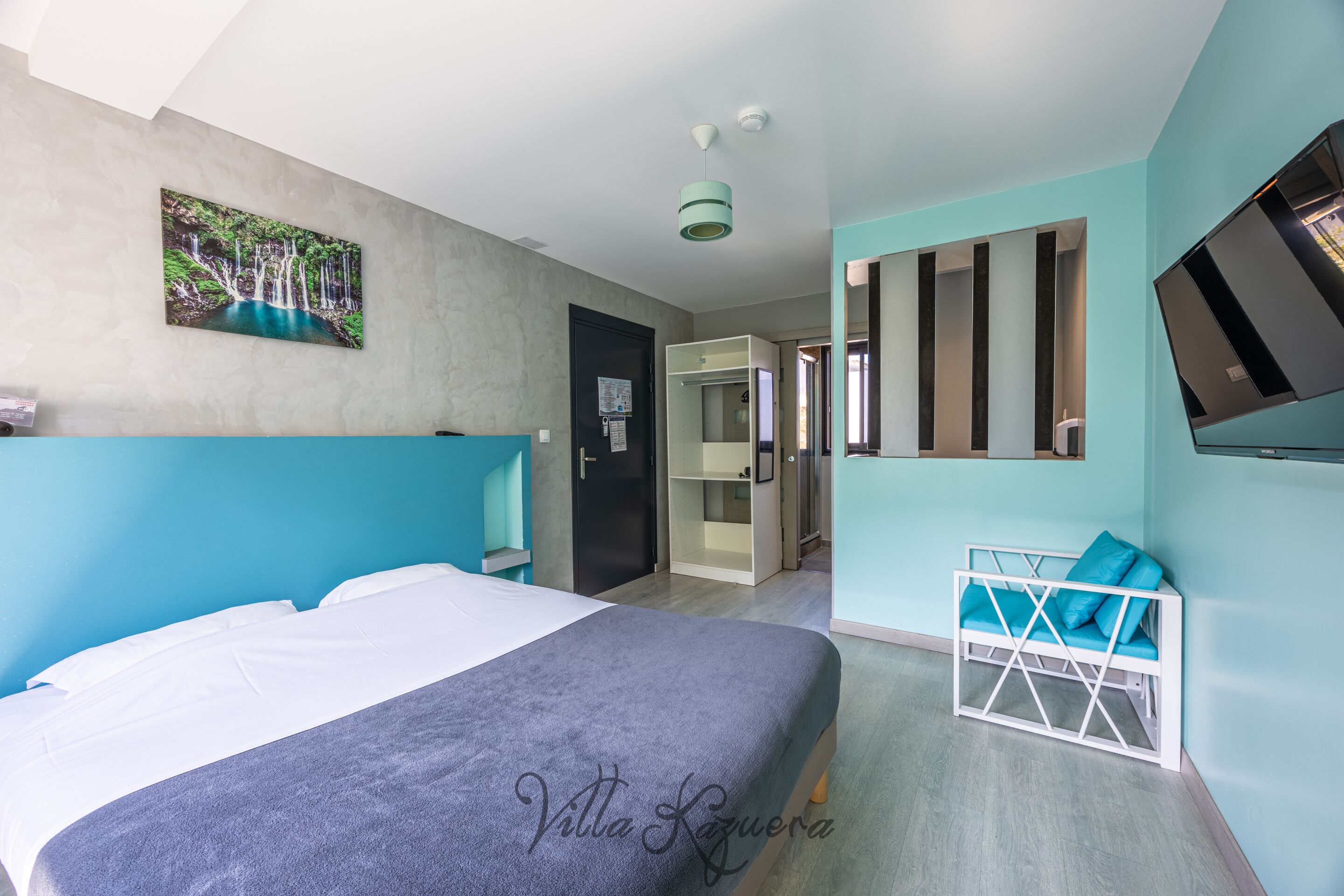 Een moderne hotelkamer met een bed, een televisie, een schilderij en een kledingkast.
