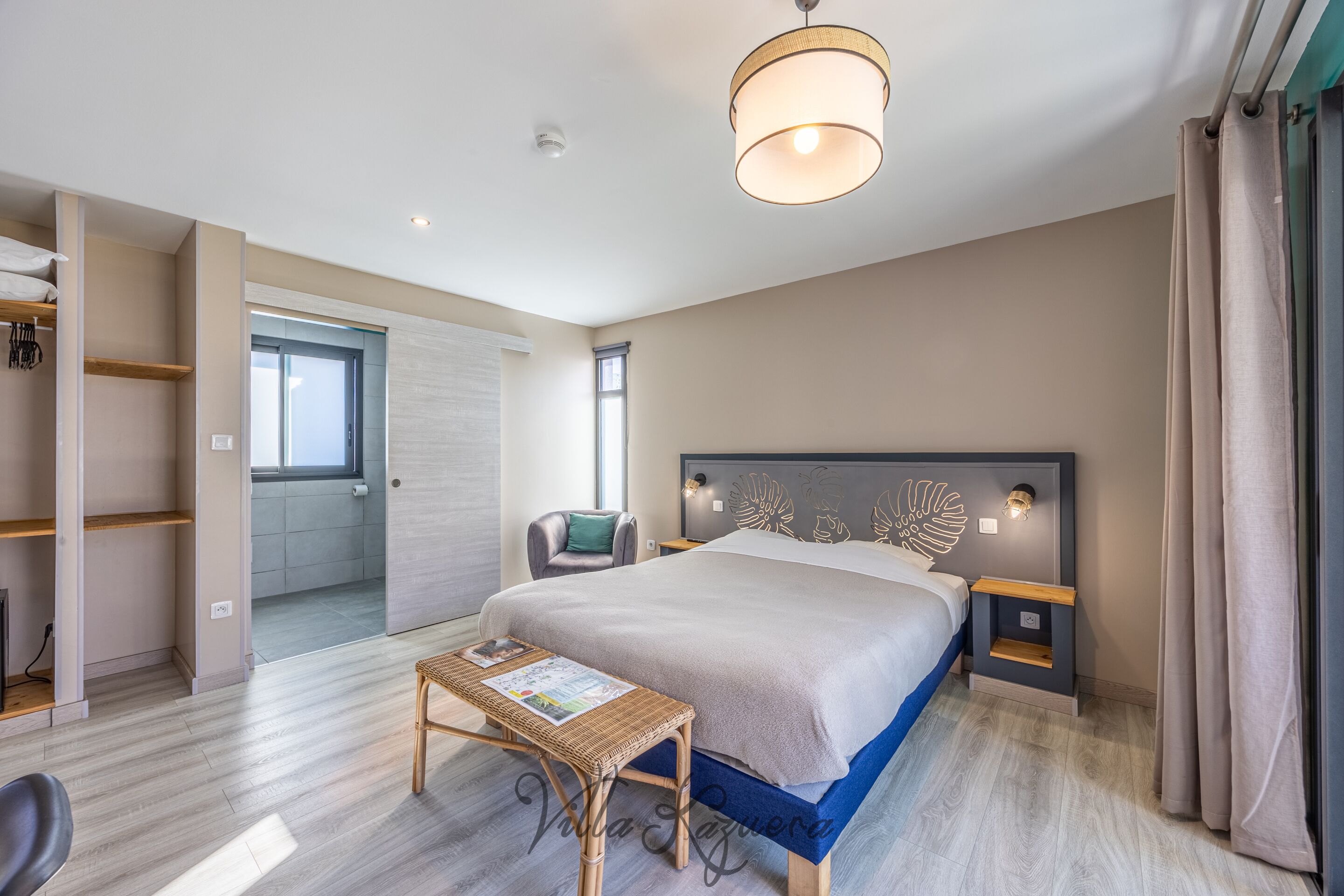 A modern bedroom with a large bed, bedside tables, a small table, and a chair.