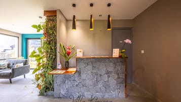 A reception area with a stone counter, potted plants, and a grey sofa.