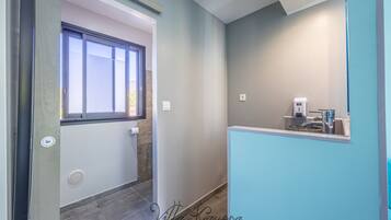 A bathroom with a window, a sink, and a towel dispenser.