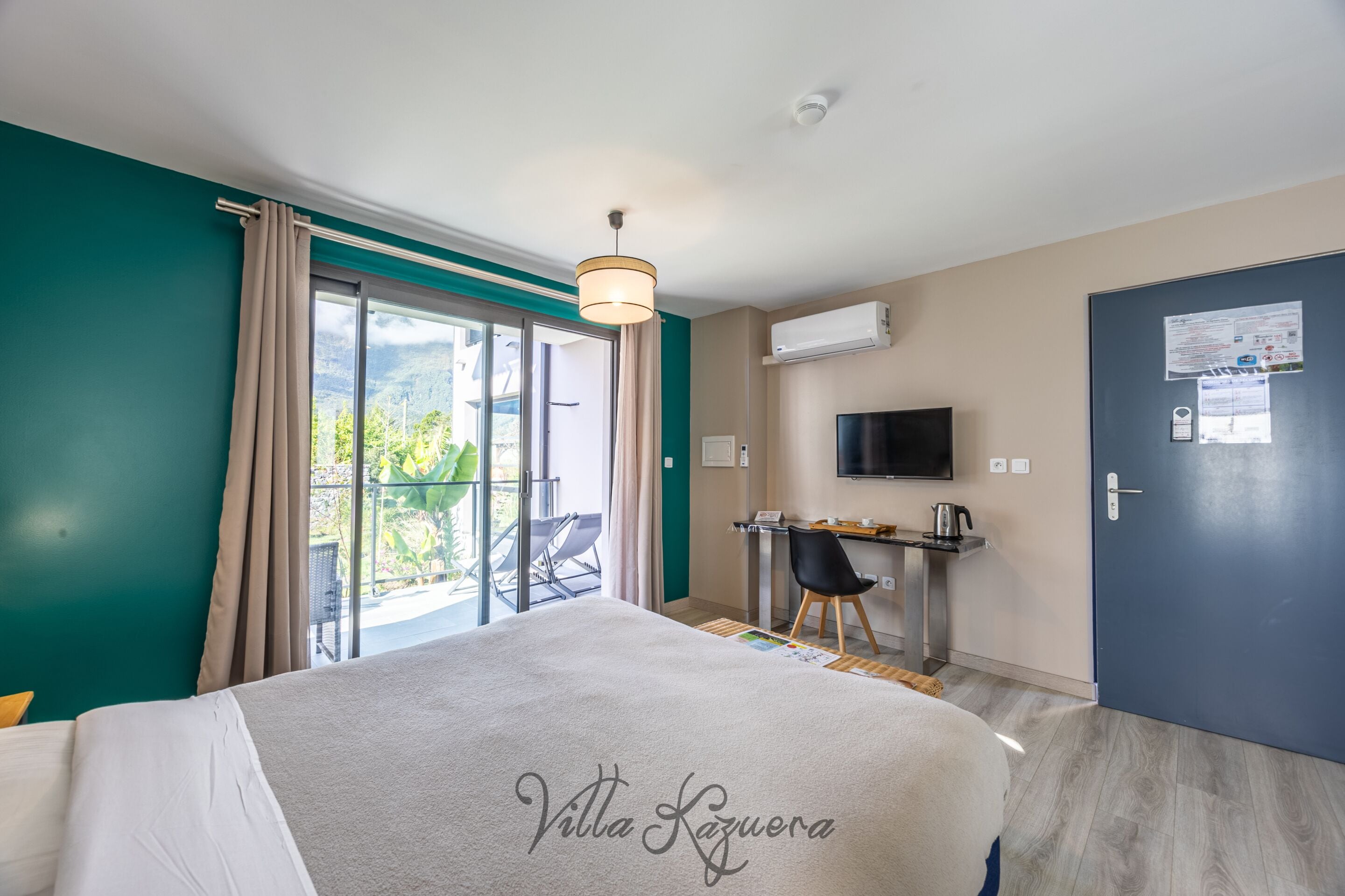 Una habitación de hotel con una cama, un escritorio, una silla, un televisor y una puerta.