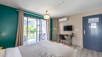 Una habitación de hotel con una cama, un escritorio, una silla, un televisor y una puerta.