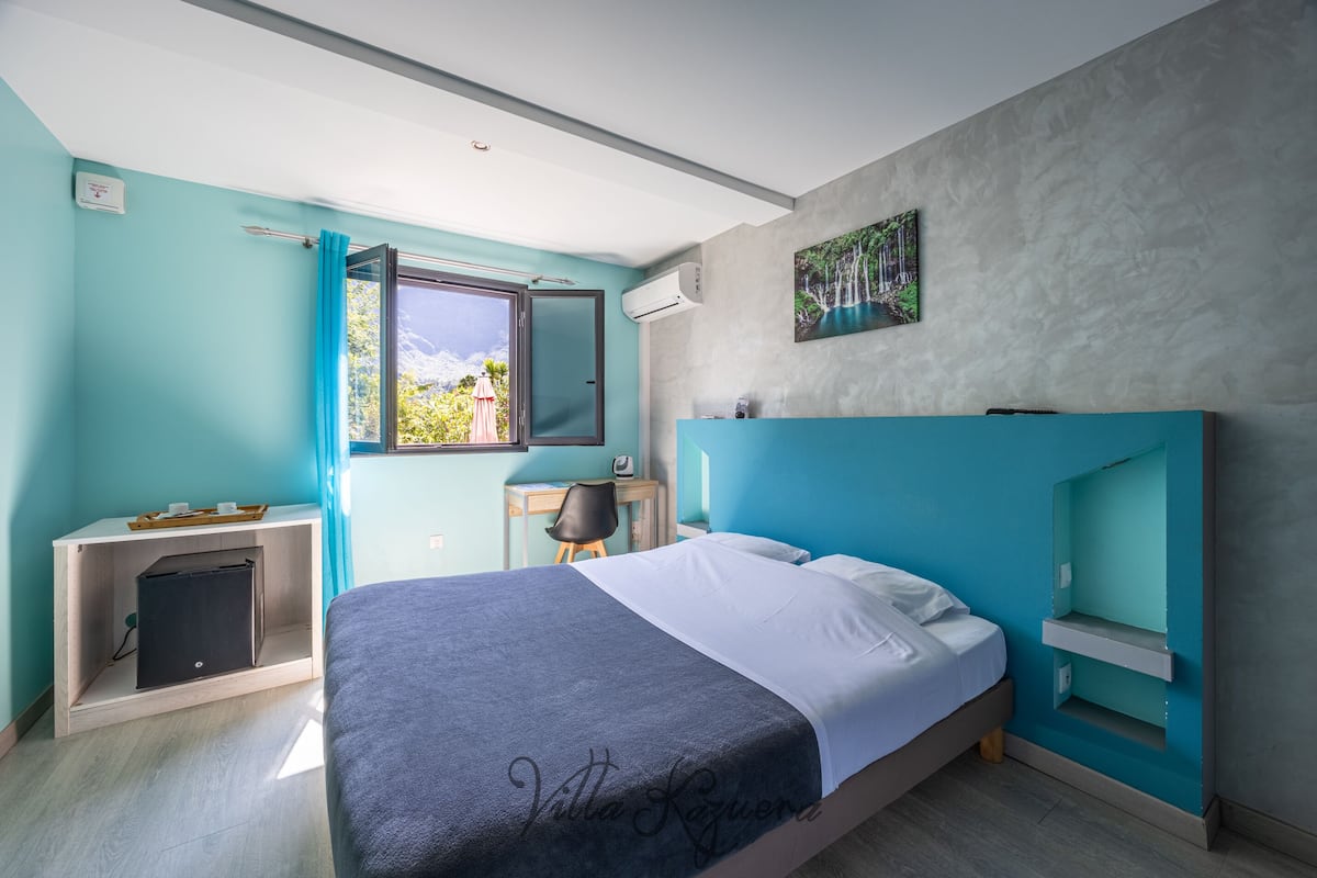 Une chambre moderne avec un grand lit, un bureau, une chaise et une fenêtre avec des rideaux.