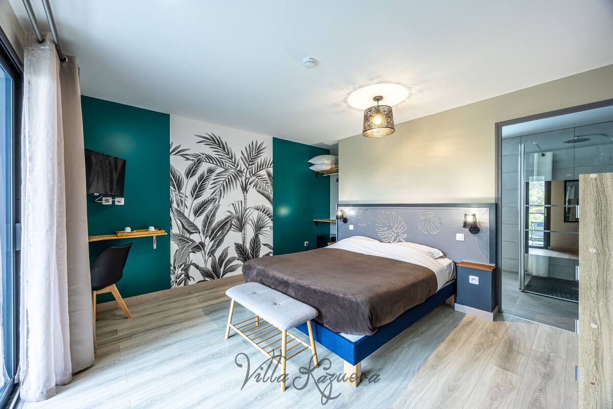 Une chambre moderne avec un lit, un banc, un bureau et une grande fenêtre.