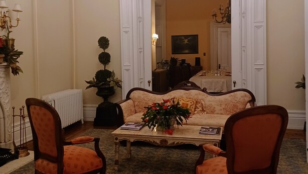 Un salon élégant, avec un canapé, deux fauteuils, un lustre et une cheminée.
