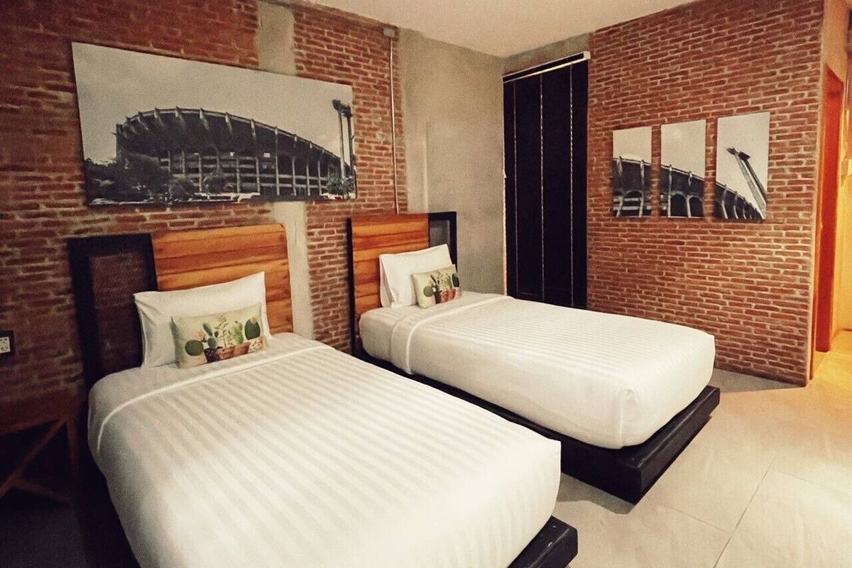 Een hotelkamer met twee bedden, een bakstenen muur en een groot raam.