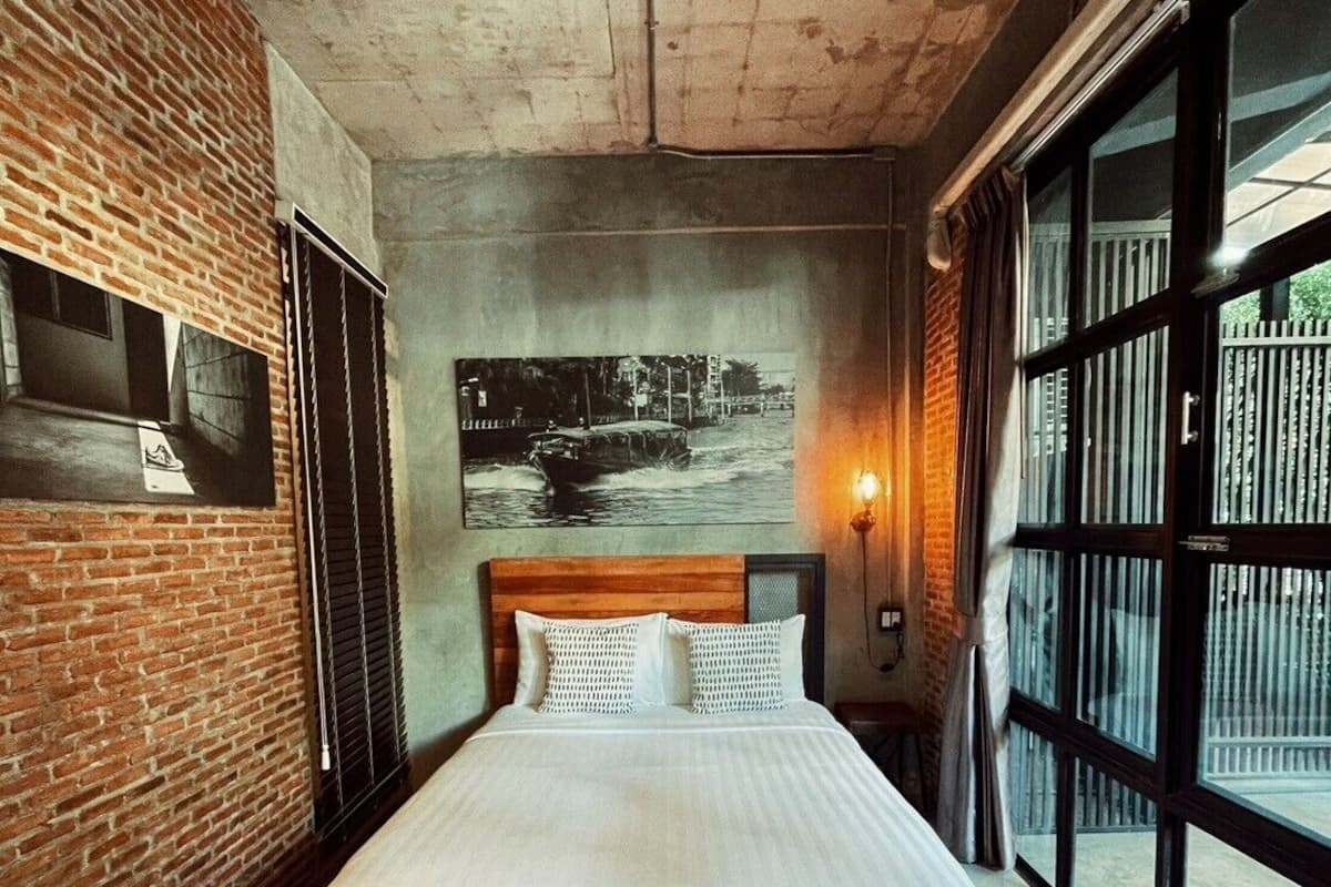 Een moderne slaapkamer met een bakstenen muur, een groot bed, een ingelijst kunstwerk en een raam met uitzicht.