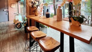 Un interior moderno con una larga barra de madera, taburetes de bar y grandes ventanales con vistas al exterior.