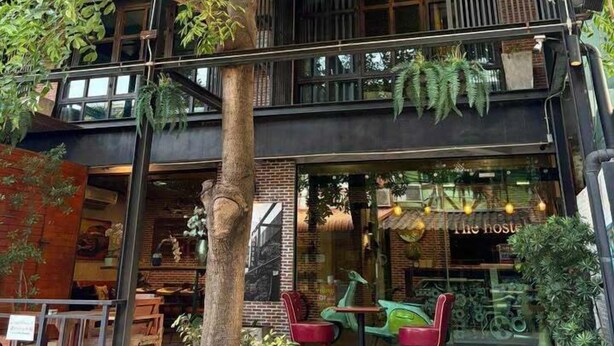 Un edificio de dos pisos con balcón, mobiliario exterior y vegetación.