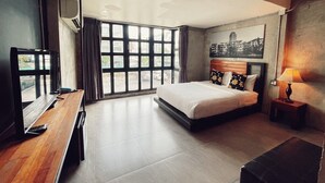 Una habitación de hotel moderna con una cama grande, un escritorio y vistas de la ciudad a través de amplios ventanales.
