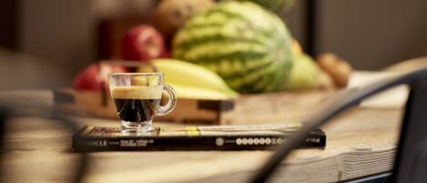Una taza de café sobre un libro, con un fondo borroso de frutas y verduras.
