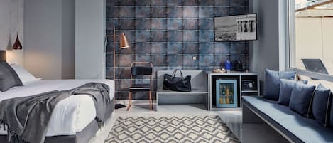 A modern bedroom with a bed, a bench, a small table, and a wall-mounted shelf.