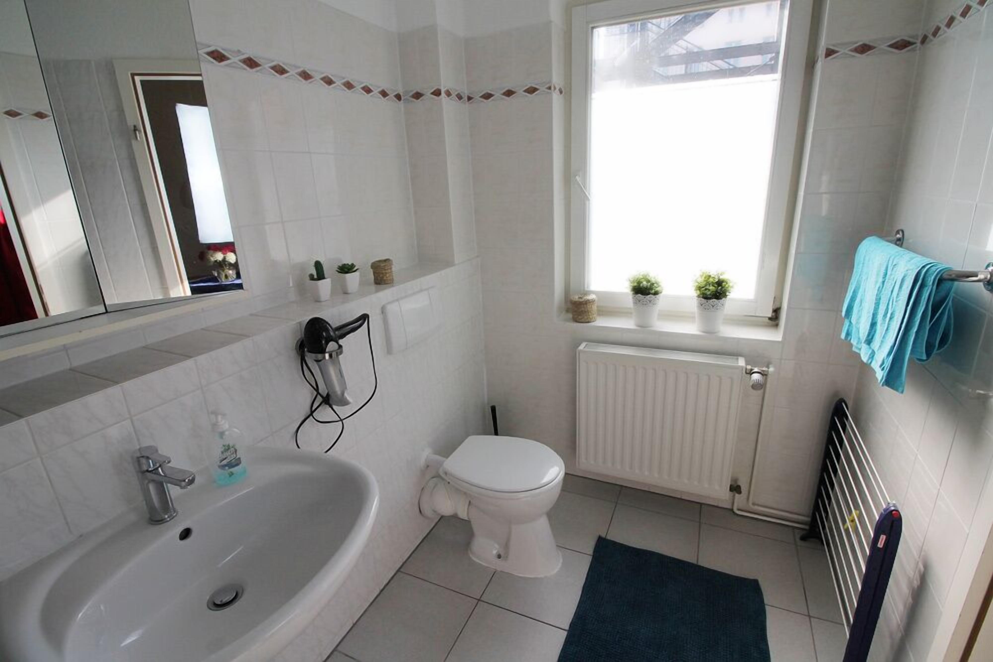 A bathroom with a bathtub, toilet, and window.