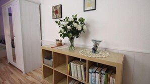 A room with a wooden console table, bookshelves, a white wardrobe, and a vase with white flowers. - Ferienwohnung Backstube König (Brandenburg an der Havel)