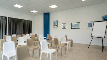 A conference room with rows of chairs, a whiteboard, and framed pictures on the wall.