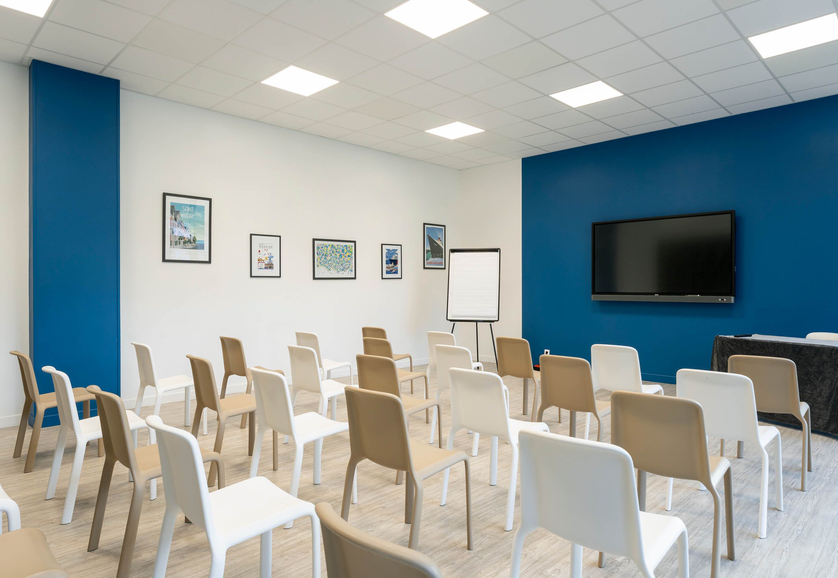 Un salón de conferencias con filas de sillas, una pizarra y una televisión en la pared.