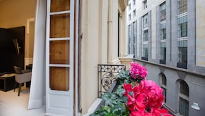 A hotel entrance with a wooden door, a white wall, and a balcony with pink flowers. - Nap Luxury Guest House (Naples)
