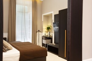 Una habitación de hotel con cama, escritorio, silla, espejo y armario.