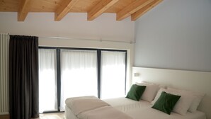 A bedroom with a large bed, a wooden ceiling, and a sliding glass door. - Borgo San Nazzaro (Riva del Garda)