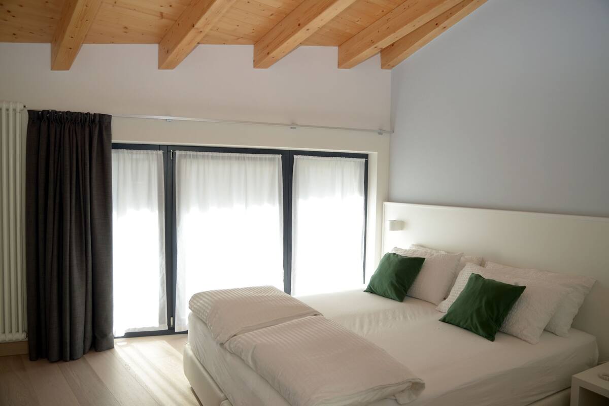 Ein Schlafzimmer mit einem großen Bett, einer Holzbalkendecke und einer Schiebeglasdoor.