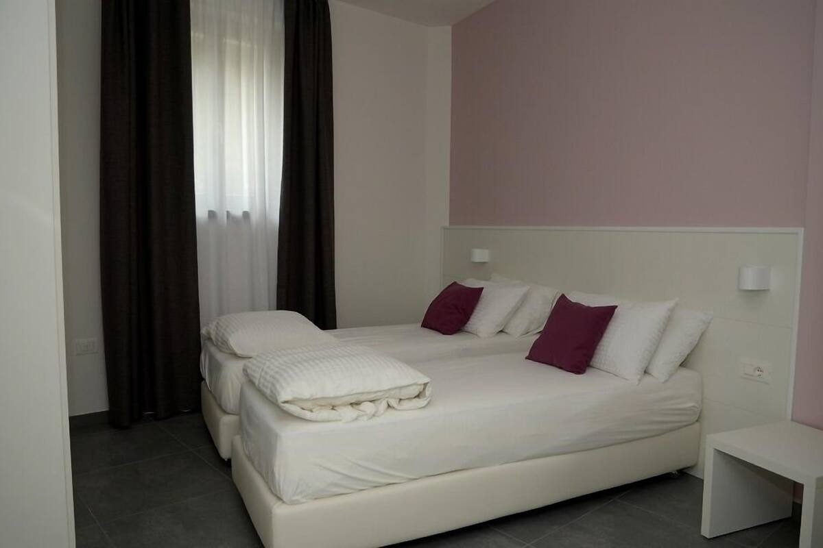 Ein Schlafzimmer mit einem Bett, einem Nachttisch und einem Fenster mit Vorhängen.