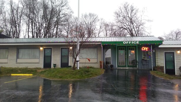 A building with a green awning labeled "OFFICE" and a neon "OPEN" sign. - Eleven E Motel (Johnson City)