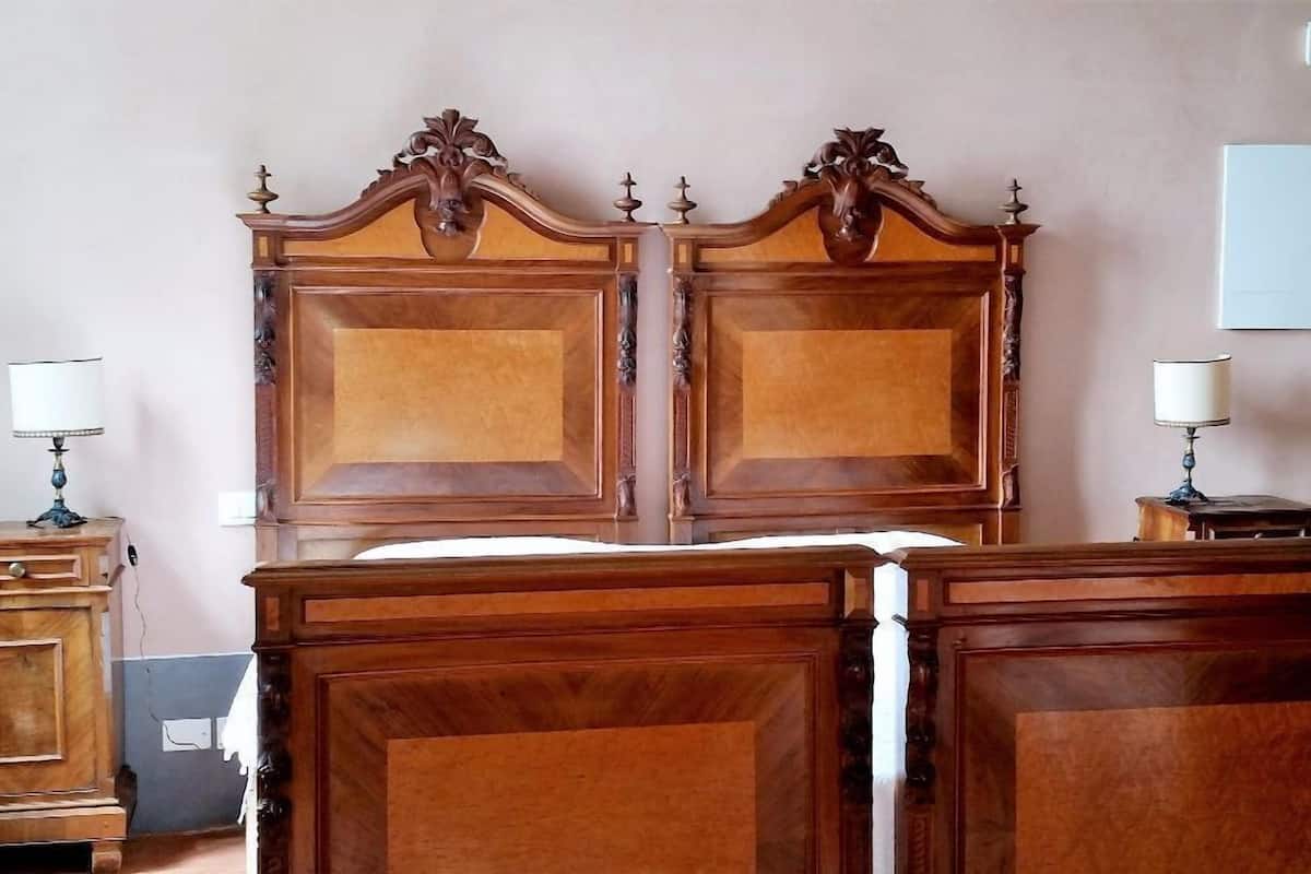 Una cama doble con cabecera de madera, una mesita de noche con lámpara y un armario.