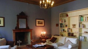 Un salon traditionnel avec une cheminée, un lustre, une bibliothèque et un canapé.