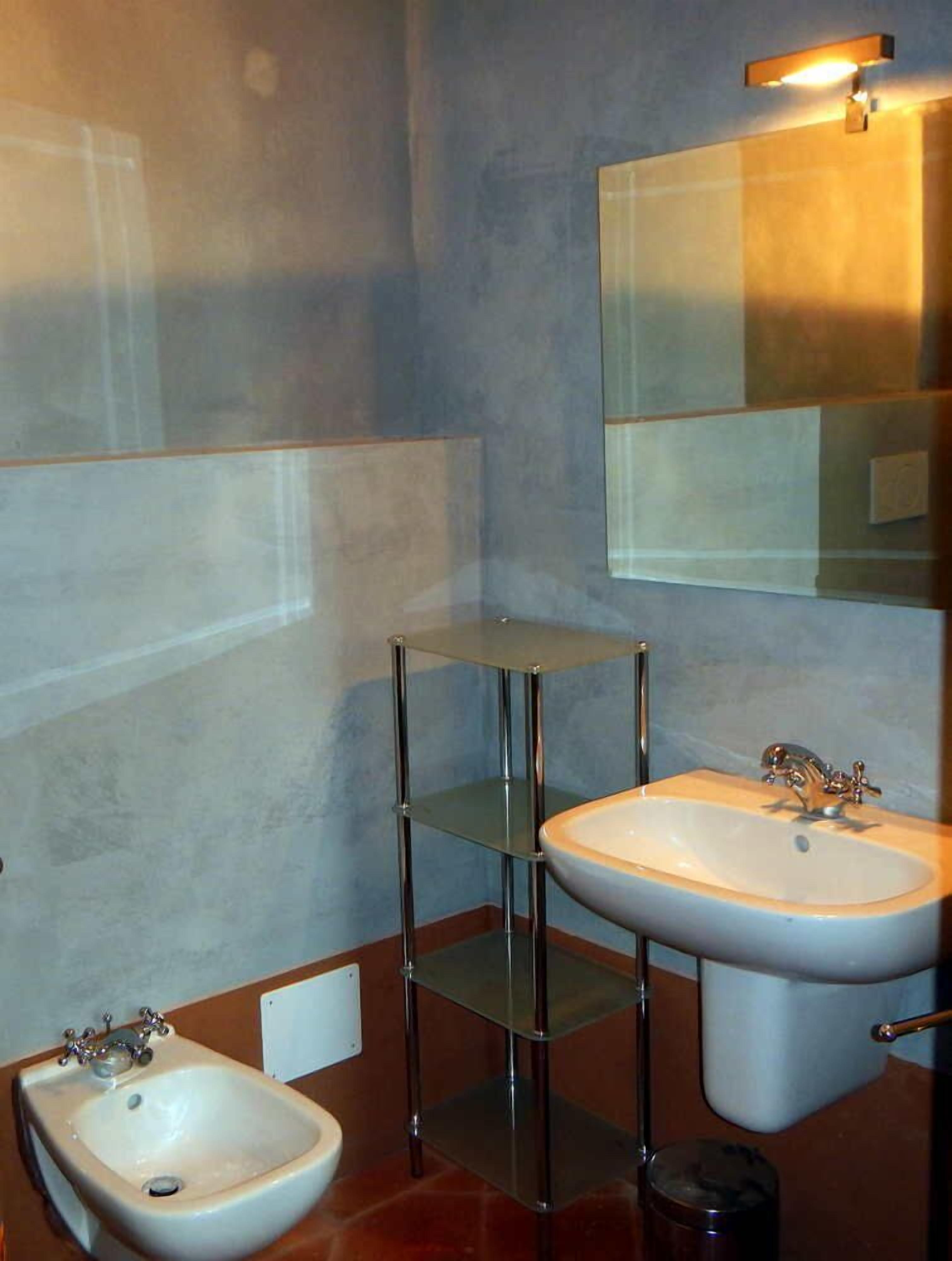 A bathroom with a white sink, a mirror, and a glass shelf.