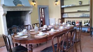 Une salle à manger avec une longue table en bois, dressée pour un repas, entourée de chaises.