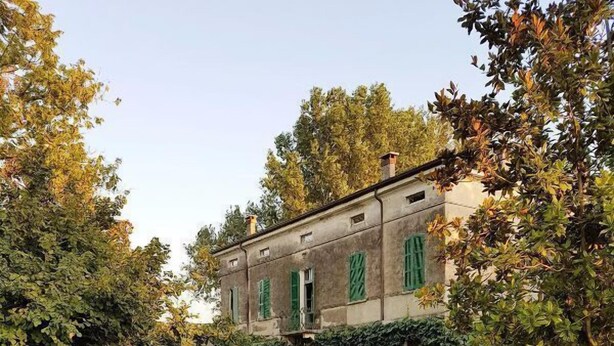 Un bâtiment à la façade symétrique, doté de grandes fenêtres avec volets et d’une pelouse bien entretenue à l’avant.