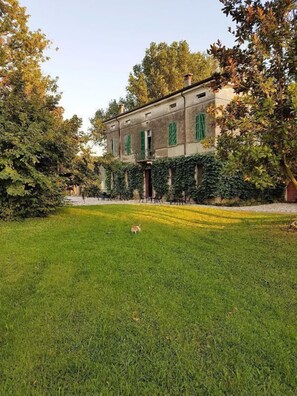 A building with a symmetrical facade, large windows with shutters, and a well-maintained lawn in front. - Corte Malpensata (San Giorgio di Mantova)