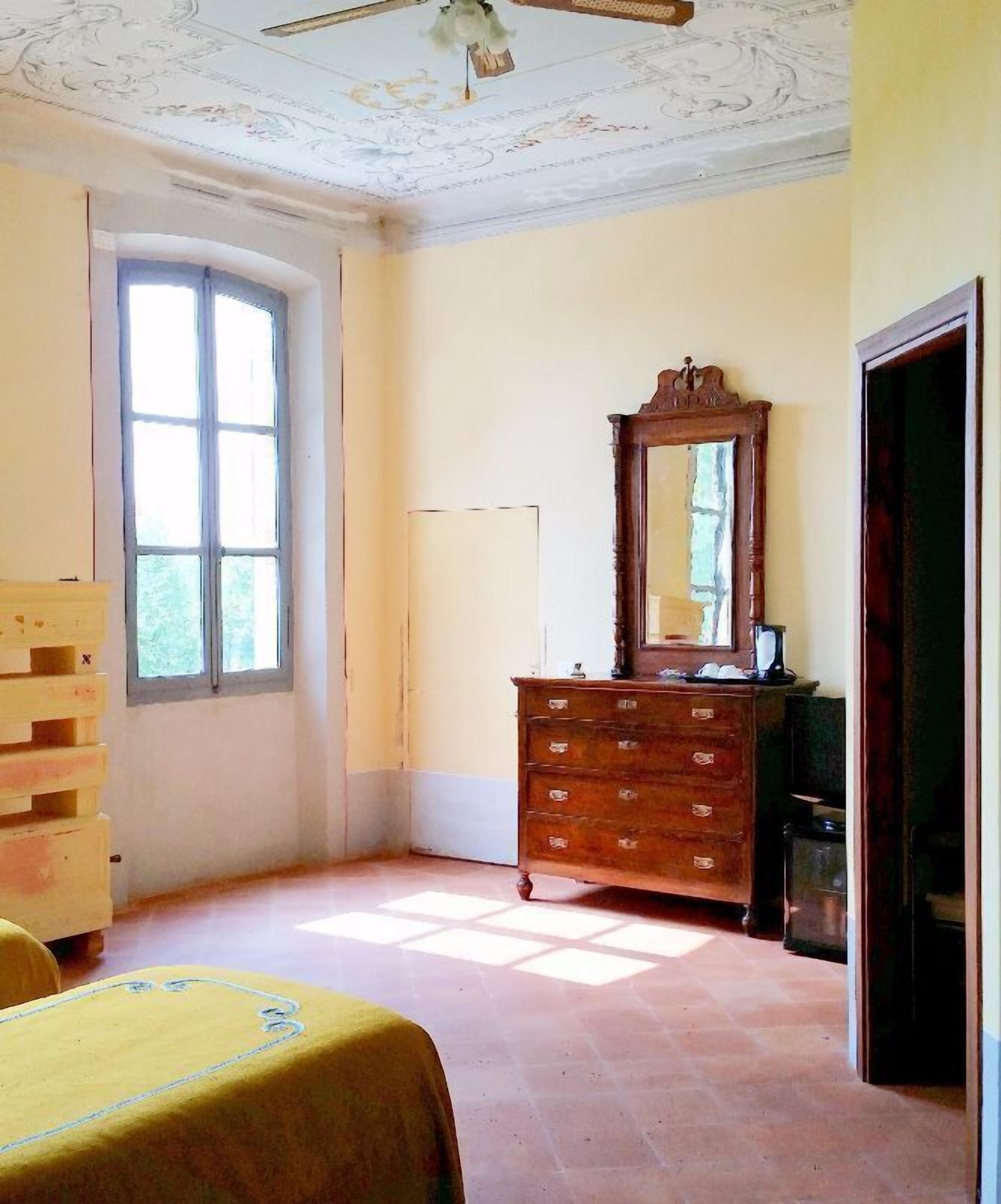 A room with a wooden dresser, a mirror, and a bed with a yellow bedspread.