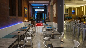 Un restaurante con una barra larga, sillas blancas y mesas con velas.