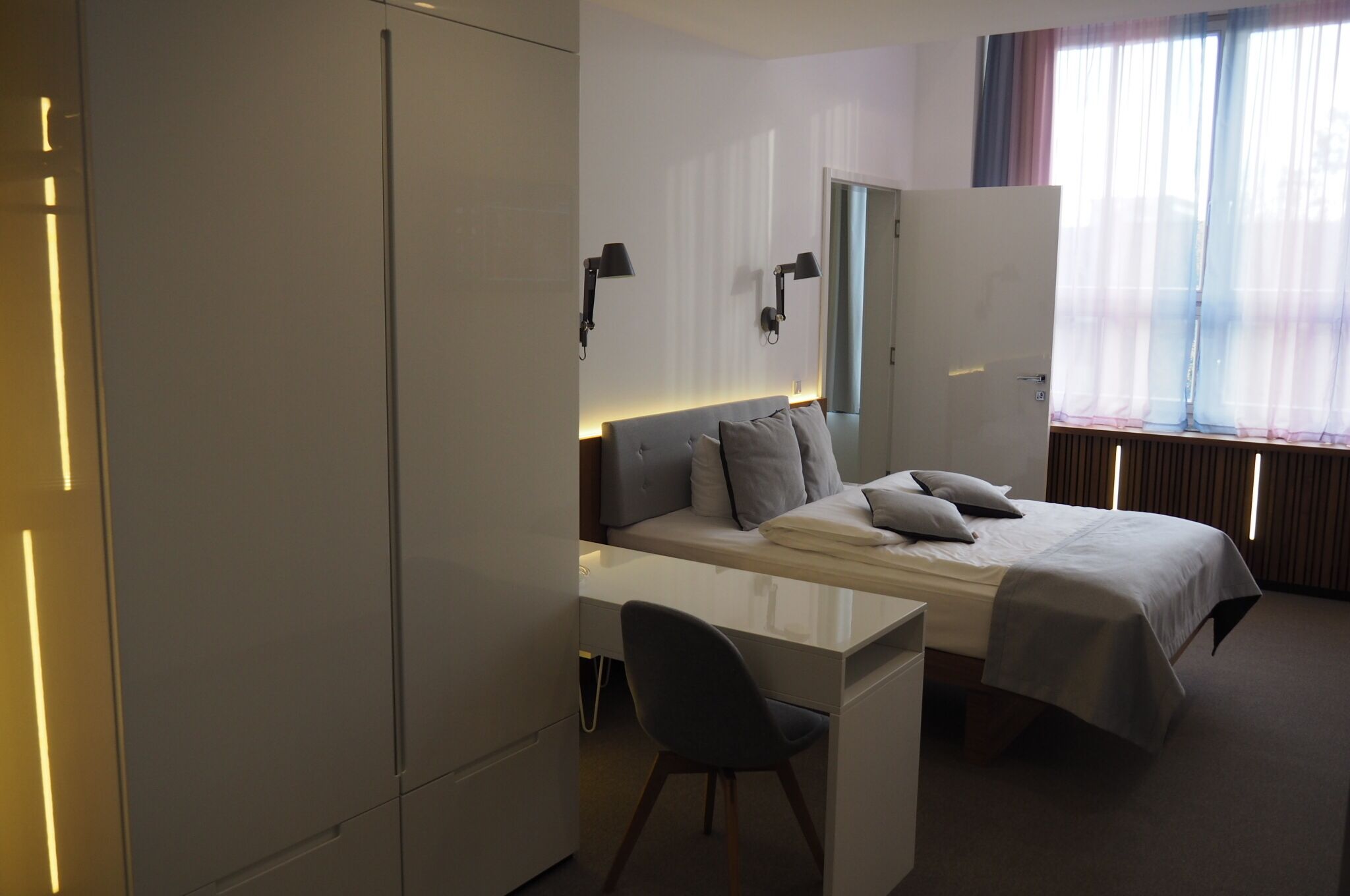 Una habitación de hotel moderna con una cama, un escritorio y una silla.